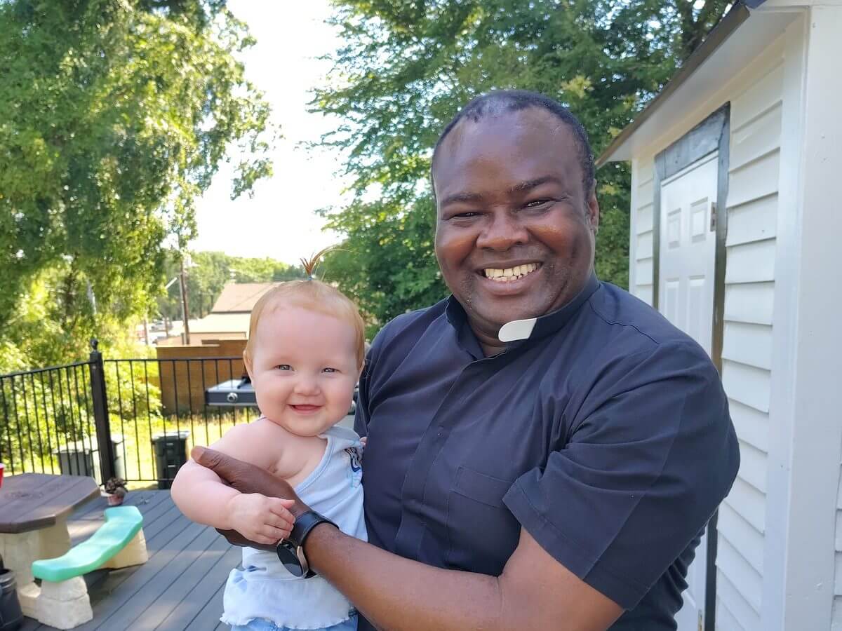 Father Felix holding a baby at Room At The Inn
